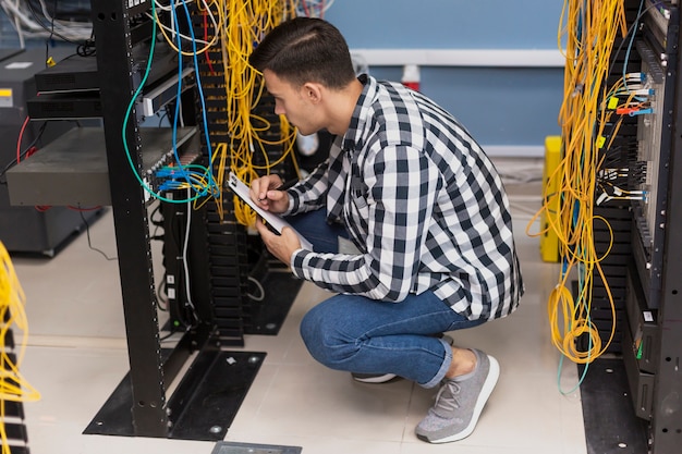 Joven ingeniero que trabaja en la sala de servidores vista de ángulo alto