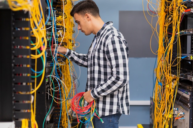 Joven ingeniero de redes con cables ethernet de tiro medio