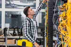 Foto gratuita joven ingeniero de redes con una caja mirando conmutadores ethernet