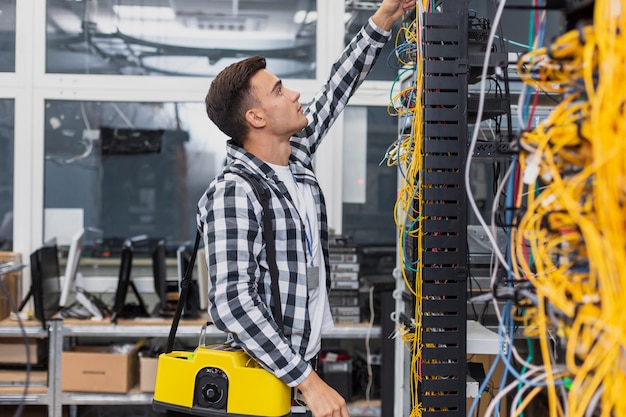 Joven ingeniero de redes con una caja mirando conmutadores ethernet