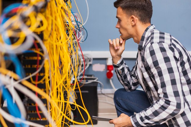 Joven ingeniero de redes mirando cables