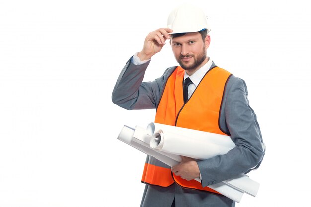 Joven ingeniero sonriendo, sosteniendo el sombrero de seguridad blanco a mano.