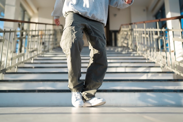 Joven intérprete masculino bailando en un edificio al lado de las escaleras