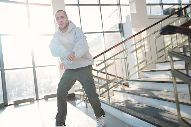 Joven intérprete masculino bailando en un edificio al lado de las escaleras