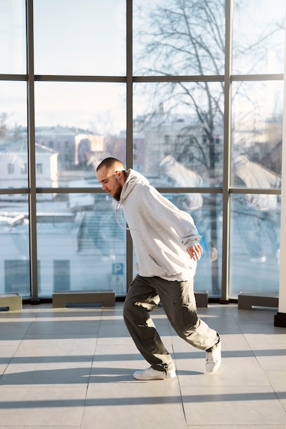 Joven intérprete masculino bailando en un edificio con grandes ventanales