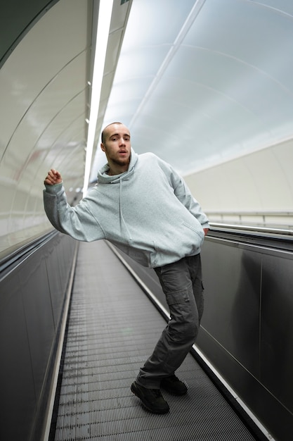 Joven intérprete masculino bailando en escaleras mecánicas