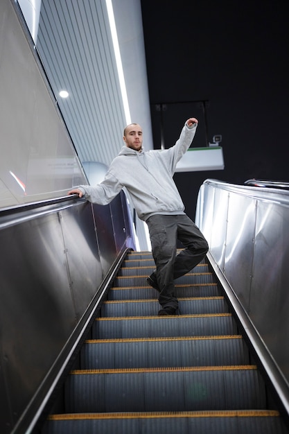 Joven intérprete masculino bailando en escaleras mecánicas