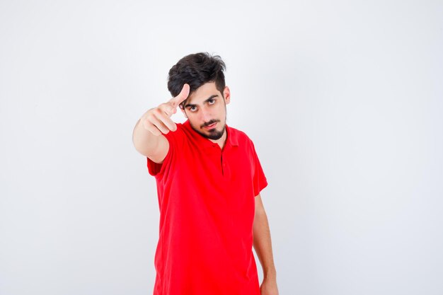 Joven invitando a venir en camiseta roja y mirando serio