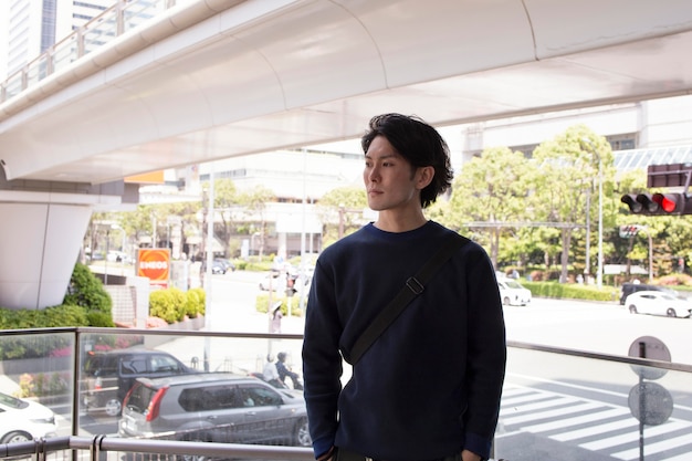 Foto gratuita joven japonés con un suéter azul en la ciudad
