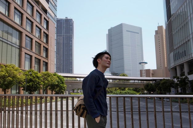 Foto gratuita joven japonés con un suéter azul en la ciudad