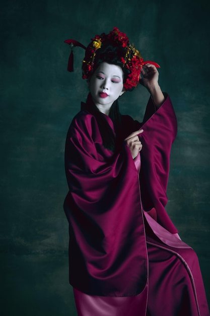 Joven japonesa como geisha en verde oscuro. Estilo retro, comparación del concepto de eras
