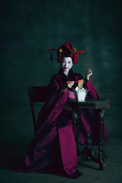 Joven japonesa como geisha en verde oscuro. Estilo retro, comparación del concepto de eras