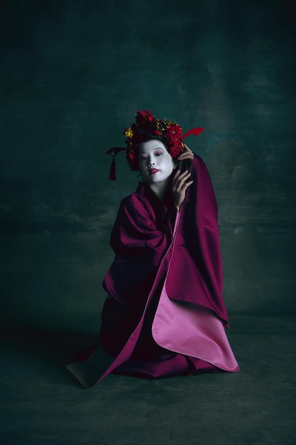 Joven japonesa como geisha en verde oscuro. Estilo retro, comparación del concepto de eras