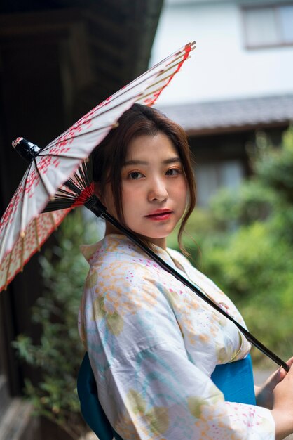 Joven japonesa vistiendo un kimono y sosteniendo un paraguas