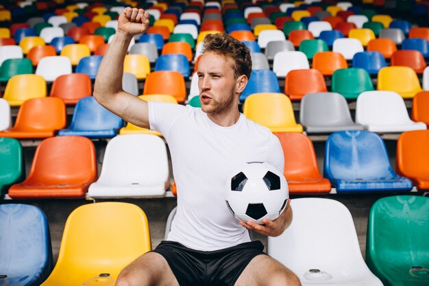 Joven jugador de fútbol en tribunas viendo el partido