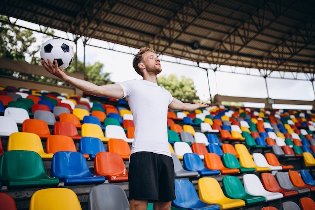 Joven jugador de fútbol en tribunas viendo el partido