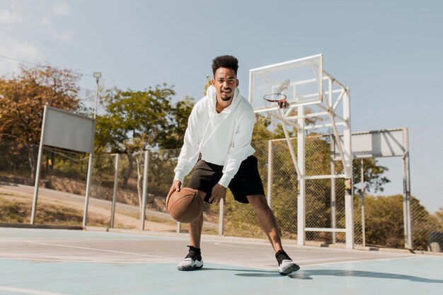 Joven jugando baloncesto en un campo