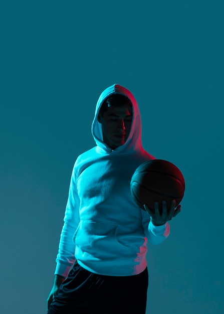 Joven jugando baloncesto con luces frías