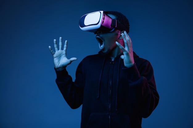 Joven jugando con gafas VR en luz de neón