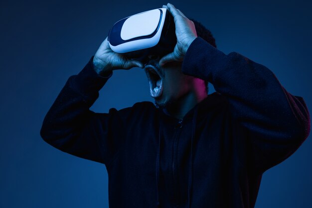 Joven jugando con gafas VR en luz de neón