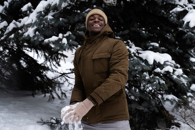 Joven jugando con nieve al aire libre el día de invierno