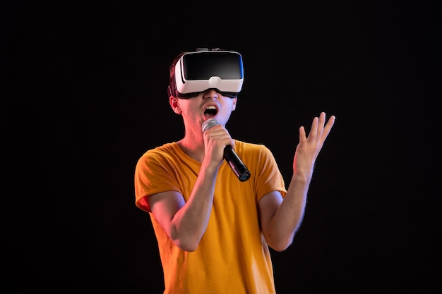 Joven jugando realidad virtual y cantando en la tecnología de juegos de visión de escritorio oscuro visual d