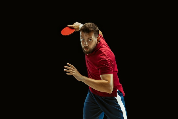 Joven jugando tenis de mesa en estudio negro