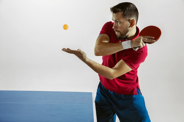 Joven jugando tenis de mesa en la pared blanca