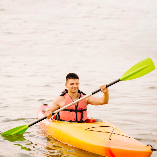 Joven kayakista masculino kayak en el lago