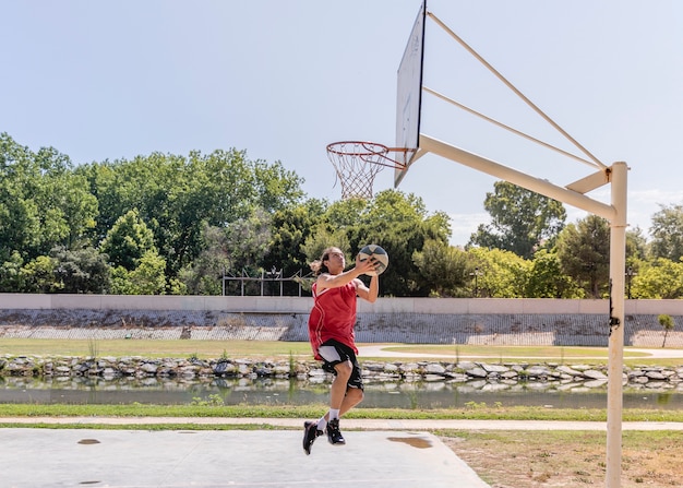 Joven lanzando baloncesto en el aro