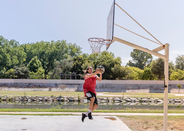 Joven lanzando baloncesto en el aro