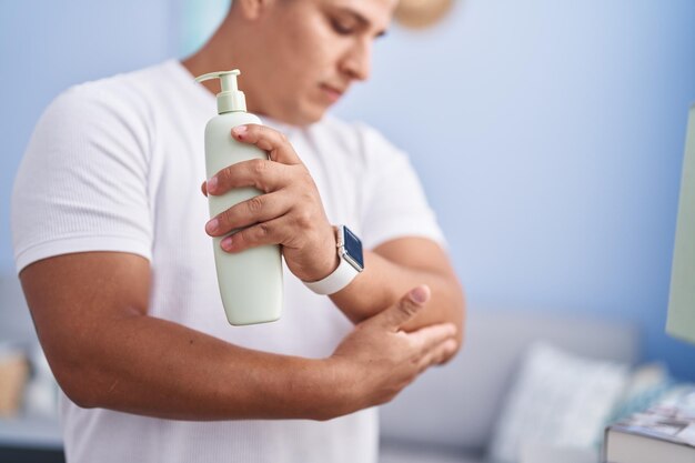 Joven latino aplicando tratamiento de piel de pie en casa