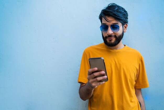 Joven latino usando su teléfono móvil.