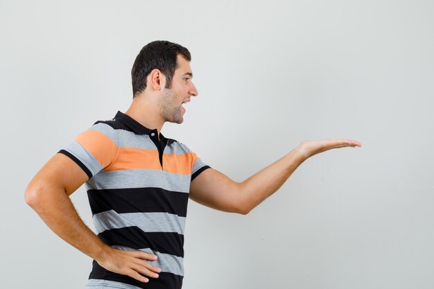 Foto gratuita joven levantando la mano para mostrar algo en la camiseta.