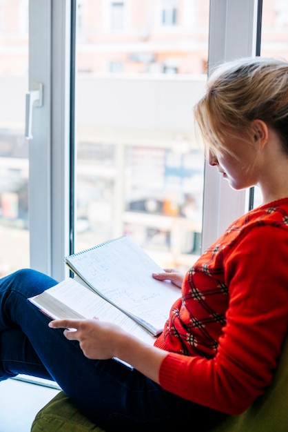 Foto gratuita joven leyendo el libro de texto