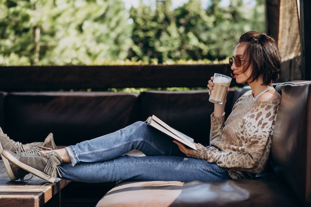 Foto gratuita joven leyendo un libro y tomando café