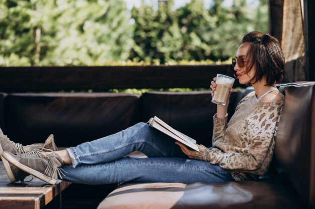 Joven leyendo un libro y tomando café