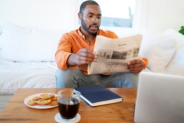 Joven leyendo el periódico en casa mientras toma un café