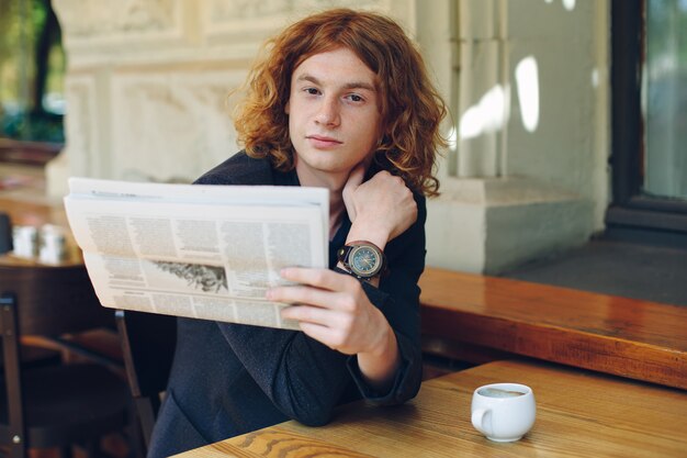 Joven leyendo un periódico en la mañana