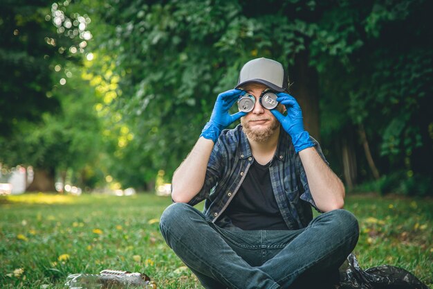 Un joven limpiando en el retrato del bosque con latas