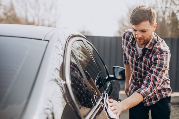 Joven limpiando su coche después del lavado de coches