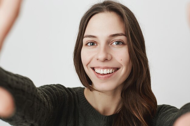 Joven linda mujer sonriendo, tomando selfie en cámara o teléfono inteligente