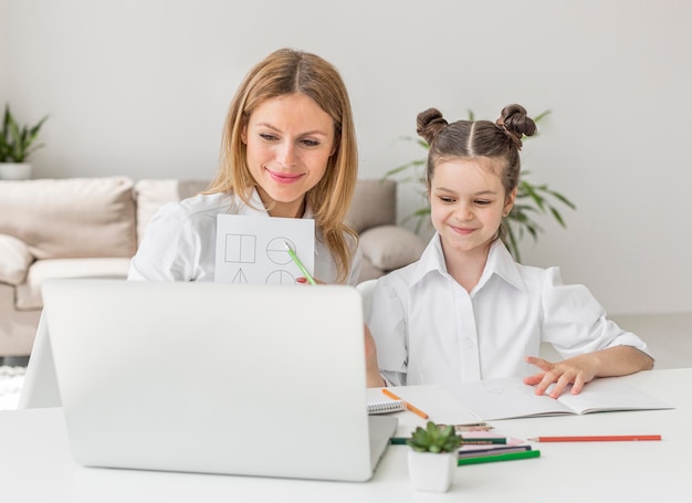 Joven madre ayudando a su hija en una clase en línea
