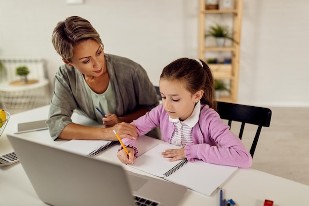 Joven madre ayudando a su hija a hacer la tarea