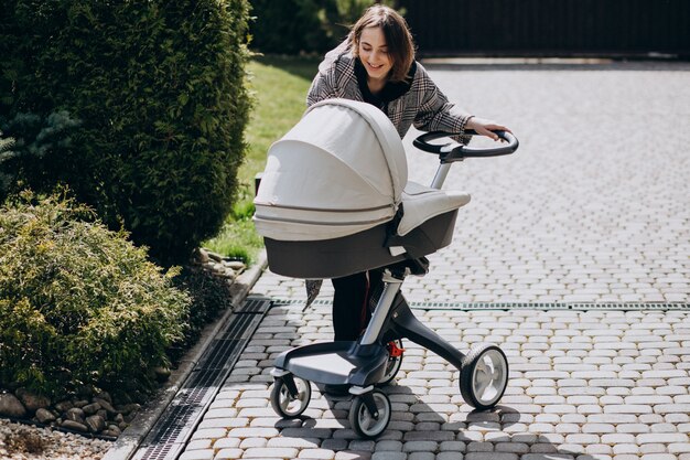 Joven madre caminando con carro de bebé en el parque