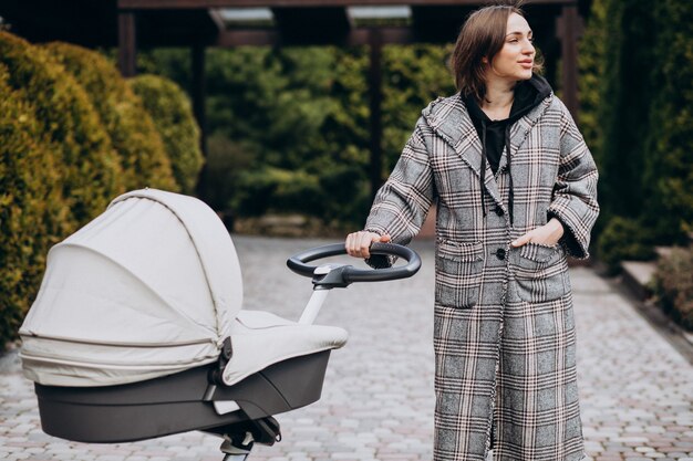 Joven madre caminando con carro de bebé en el parque