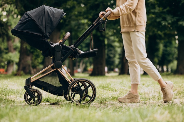 Joven madre caminando con carro de bebé en el parque