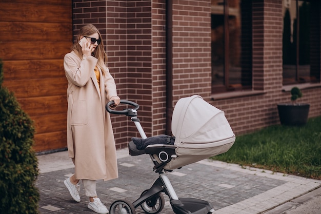 Joven madre caminando con cochecito de bebé