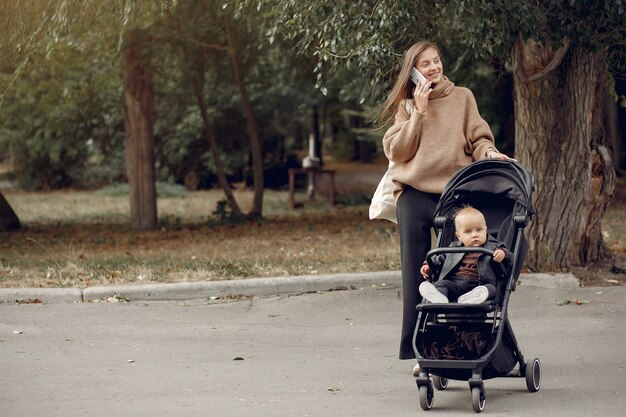 Joven madre caminando en un parque de otoño con carro