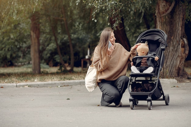 Joven madre caminando en un parque de otoño con carro